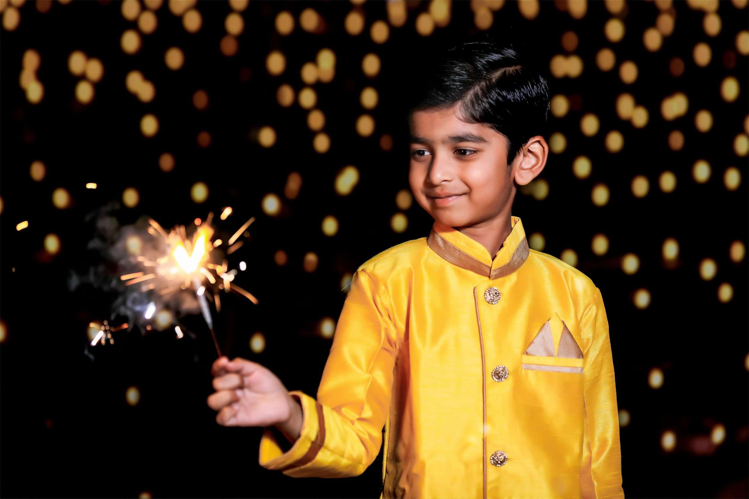 A young Indian boy lights a sparkler.